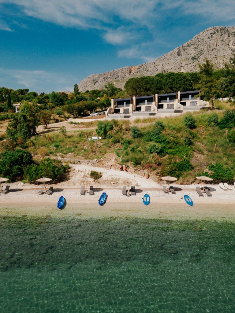 A drone photo showing the Estia Ionian Villas in the background and the secluded beach in front of it. This is one of the best Paleros beaches.